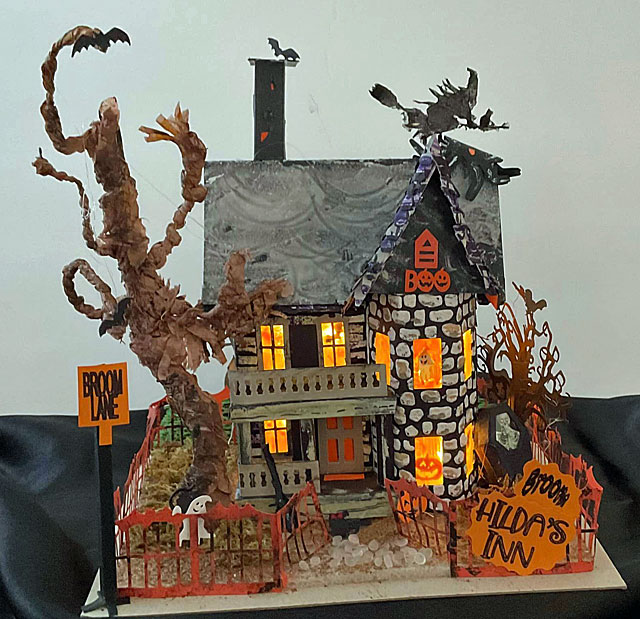Spooky cardboard Halloween house with signs for Broom Hilda's Inn