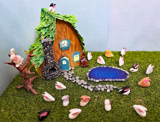Fairy house with lots of bunnies in the yard.