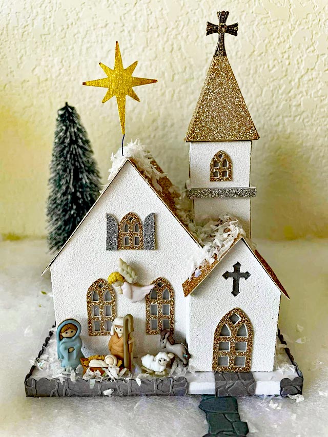 Gold and white miniature church with nativity scene in front