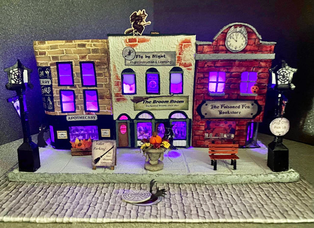 Cardboard street scene with Fly By Night flight school and Poisoned Pen bookstore