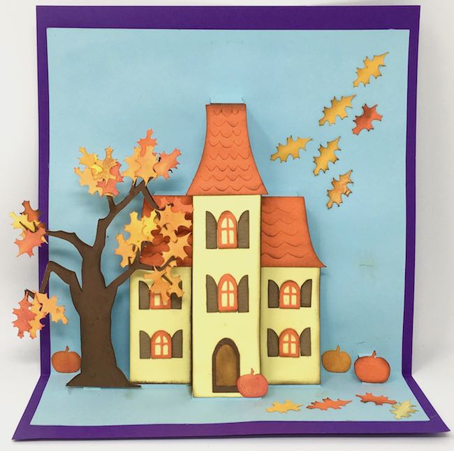 Autumn house in yellow, orange, and brown with fall leaves and pumpkins scattered about