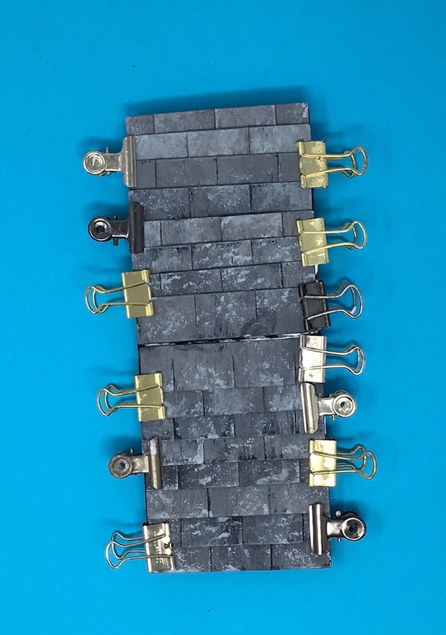 Binder clips hold the cardboard shingles to paper doghouse roof
