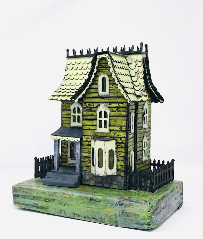 Green Halloween house with black fence