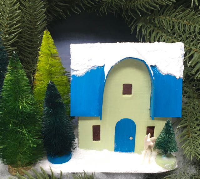 Front of Round Arch Christmas Putz house no 7 with snowy, glittered roof in a forest of bottlebrush trees on a wreath