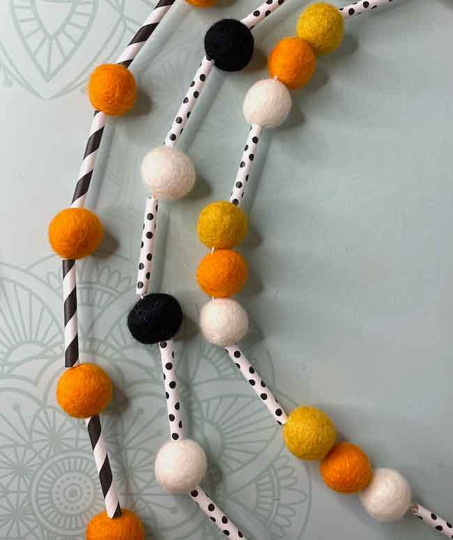 Halloween Felt Ball Garland with paper straw segments and orange black and white felt balls