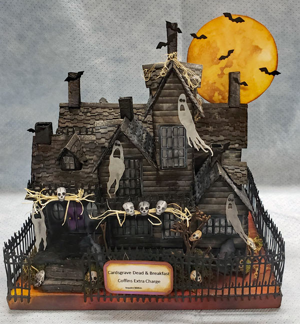 Brown and grey cardboard inn with moon and bats