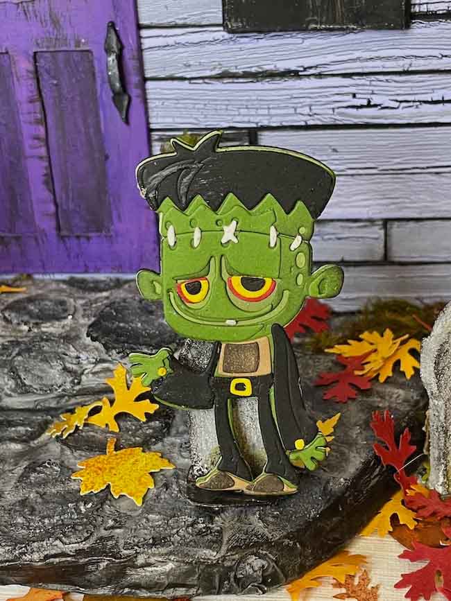 Monster layered paper figure in front of dollhouse