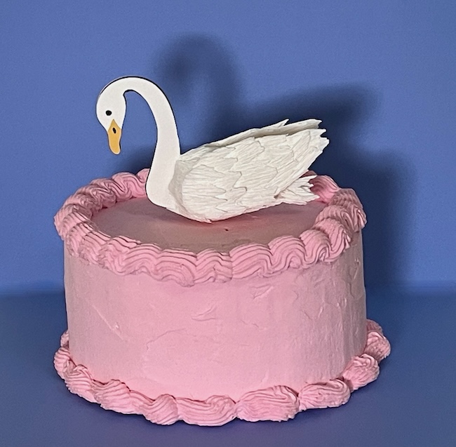 Swan cake topper on pink fake cake
