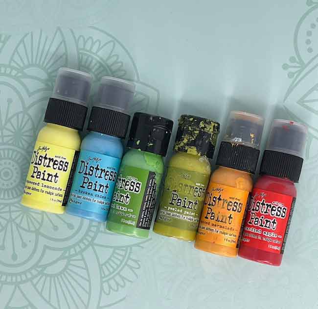 Tim Holtz Distress paint bottles showing the range of colors available