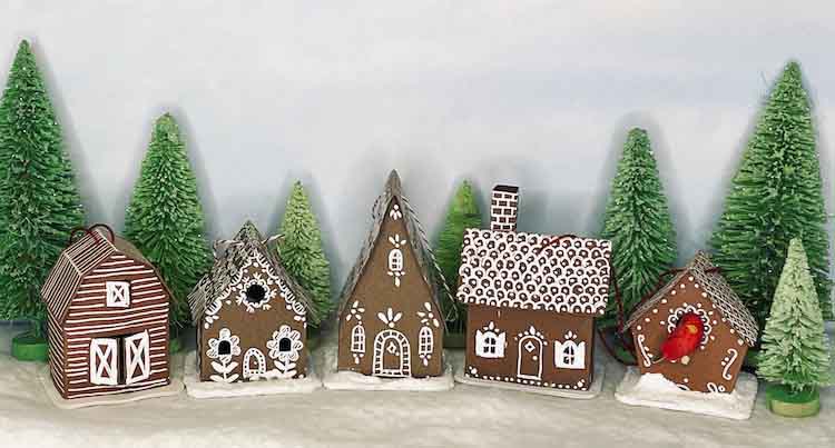 5 tiny paper houses of brown cardstock with white decorations with tiny green trees
