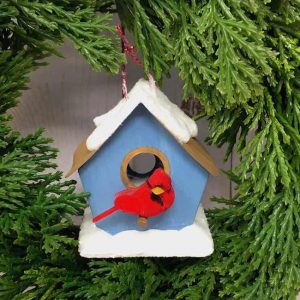 Tiny red cardinal on blue birdhouse with snow on roof