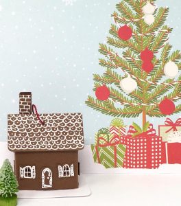 tiny brown paper cottage ornament with Christmas tree background