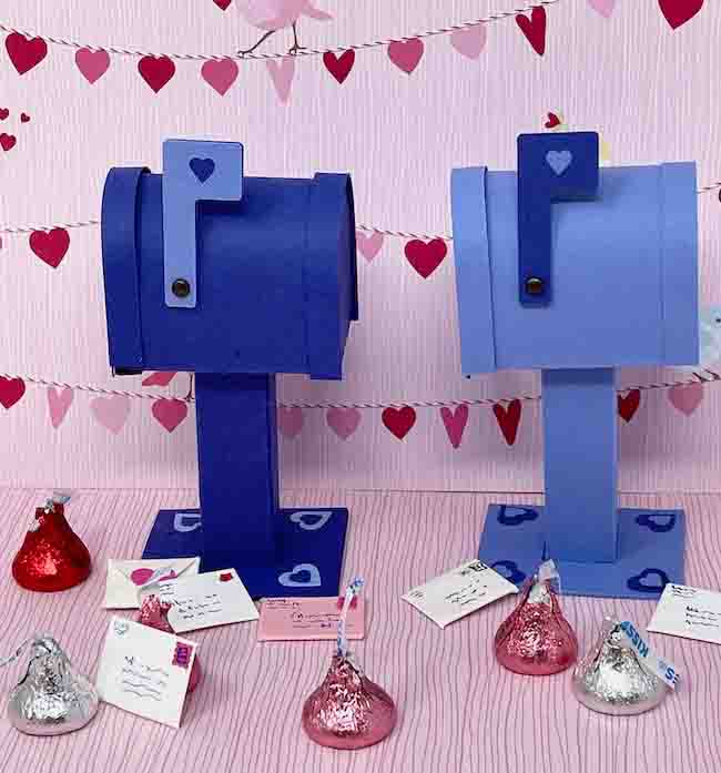 two miniature blue mailboxes with letters candy around the base